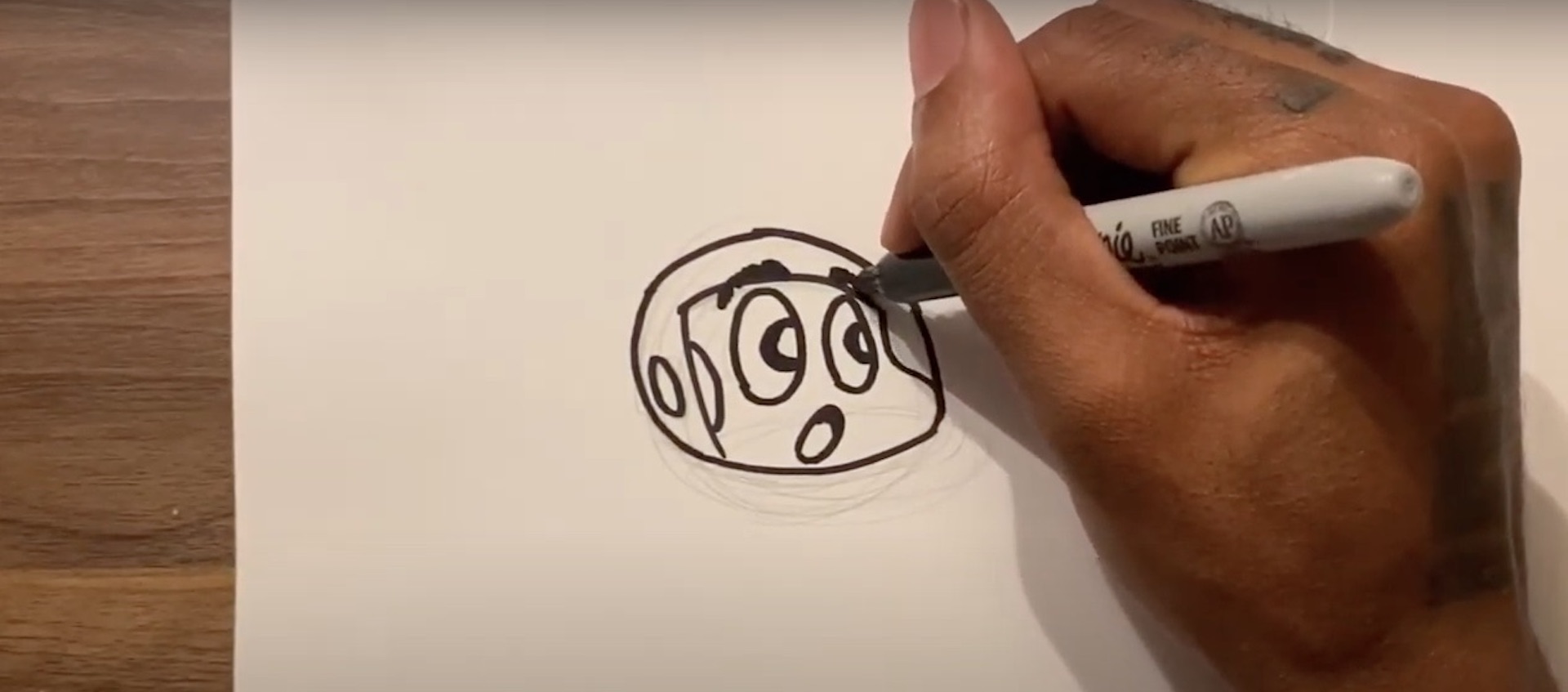 The hand of artist Hakim Callwood draws the head of his cartoon character Spaceboy