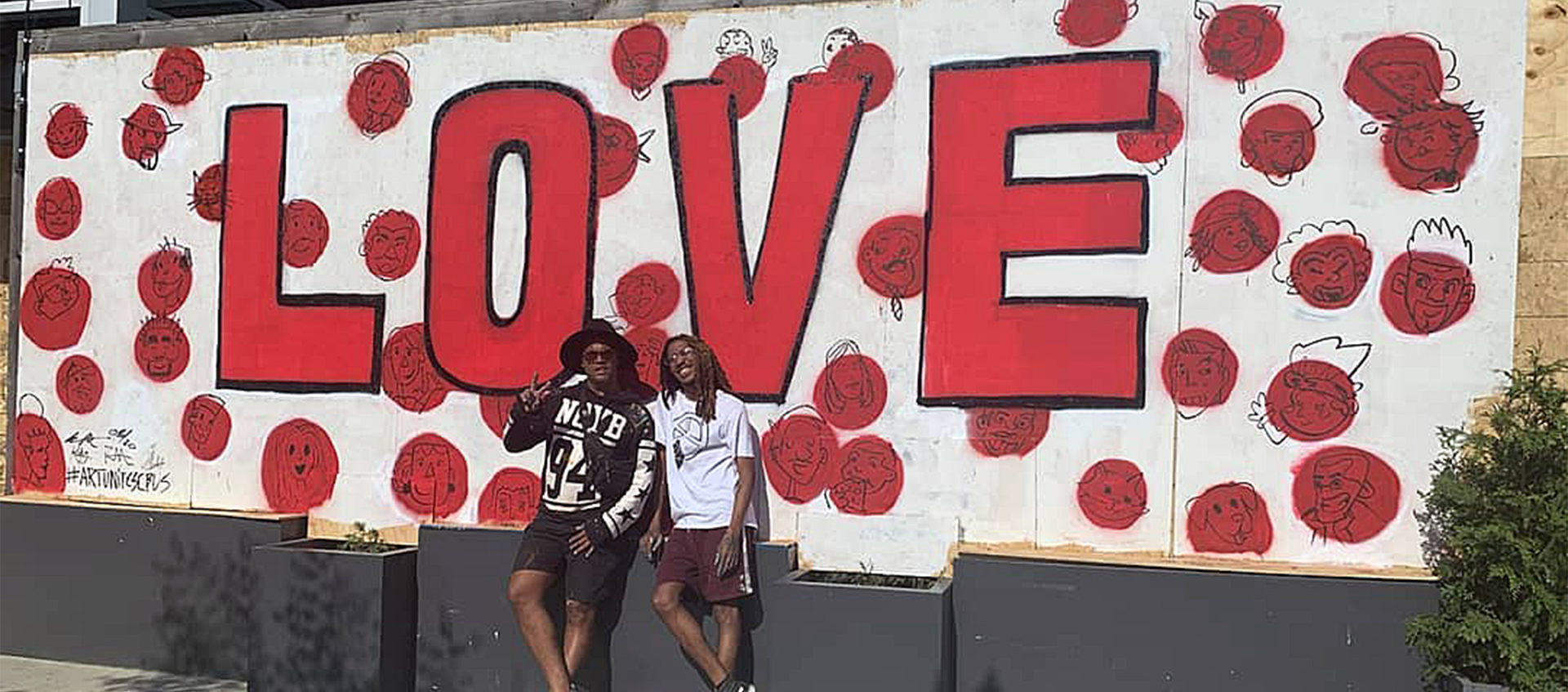 Columbus artists Bryan Moss and Hakim Callwood stand in front of a "Love" mural on the front of Donato's in the Short North