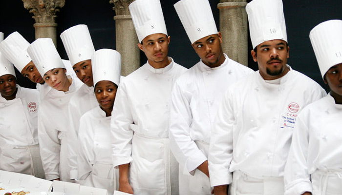A row of people are lined up wearing chef hats.